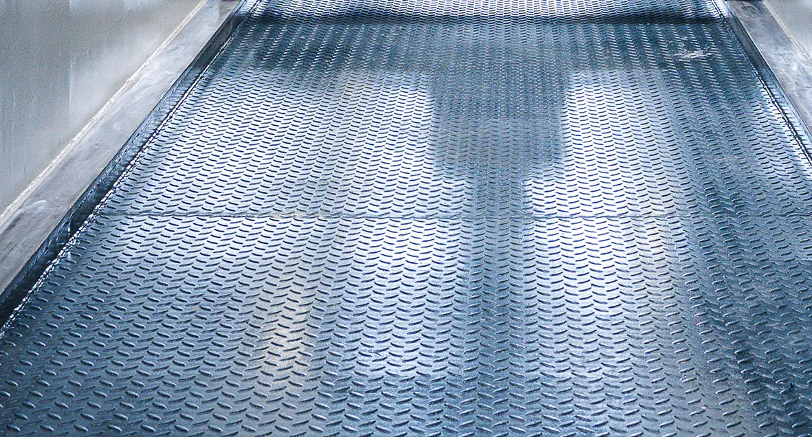 Robuster Riffelblech-Bodenbelag in einer Werkstattgrube für Nutzfahrzeuge. Die Aufnahme zeigt die rutschfeste und widerstandsfähige Bodenlösung für sichere Arbeitsbedingungen bei Wartungs- und Servicearbeiten.