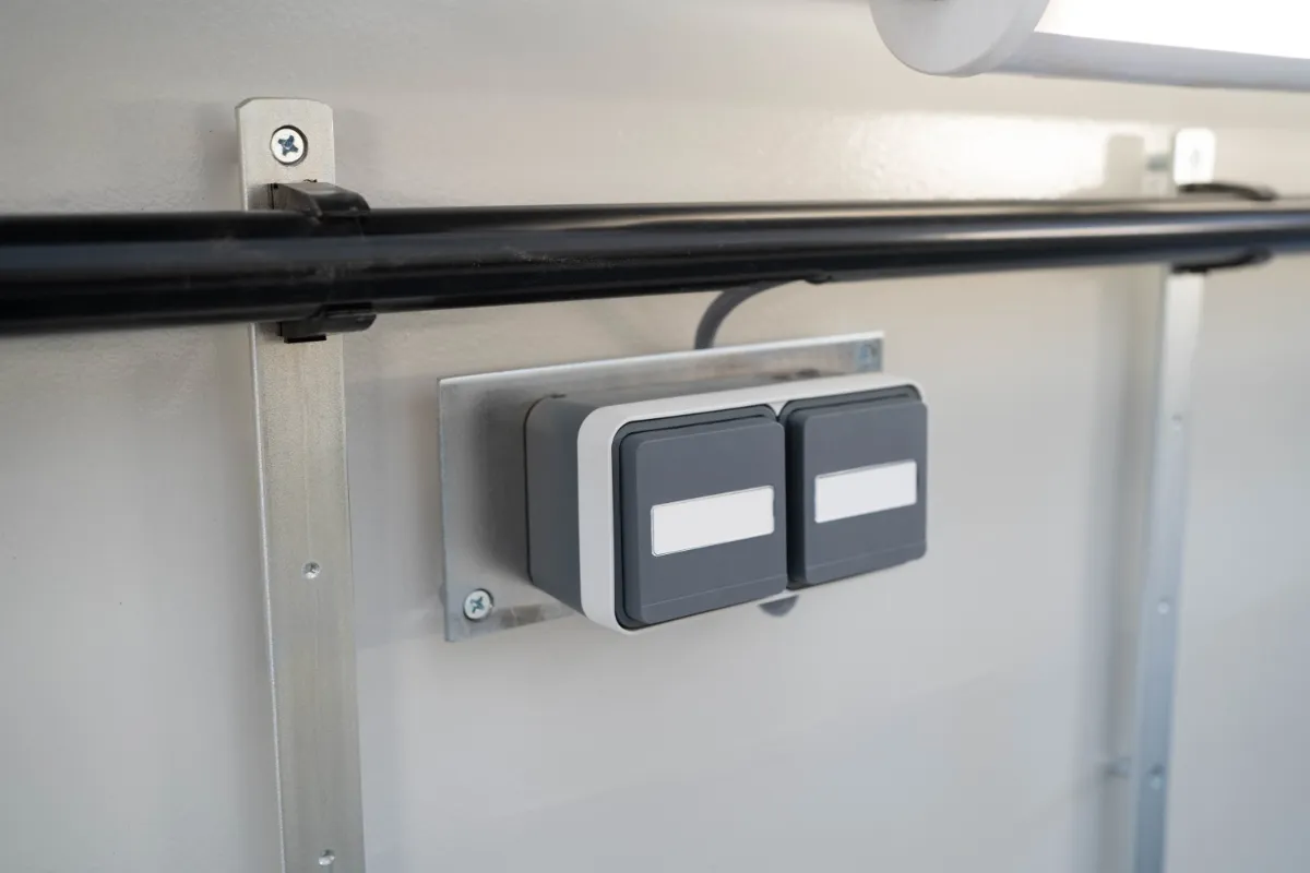 Nahaufnahme eines elektrischen Schaltersystems innerhalb einer truckcon Werkstattgrube. Die Aufnahme zeigt die sauber integrierte Elektroinstallation für Beleuchtung und technische Versorgung in modernen Nutzfahrzeugwerkstätten.