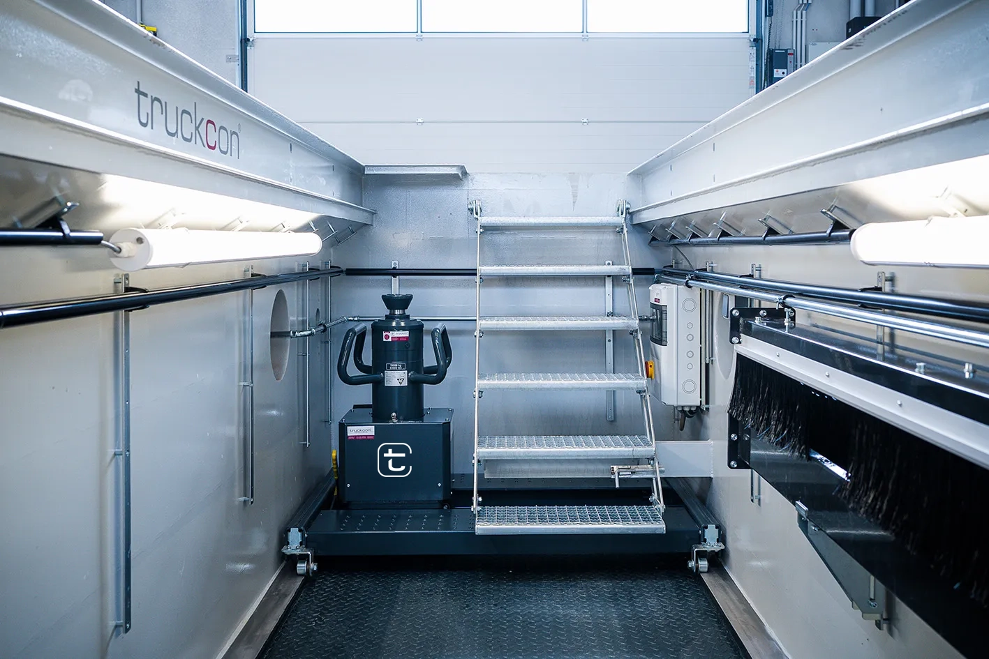 Moderne truckcon Montagegrube mit verzinkter Zugangstreppe, integrierter Beleuchtung und bodenlaufendem Grubenheber. Die Aufnahme zeigt eine funktional ausgestattete Wartungsgrube für professionelle Arbeiten an LKWs und Nutzfahrzeugen.